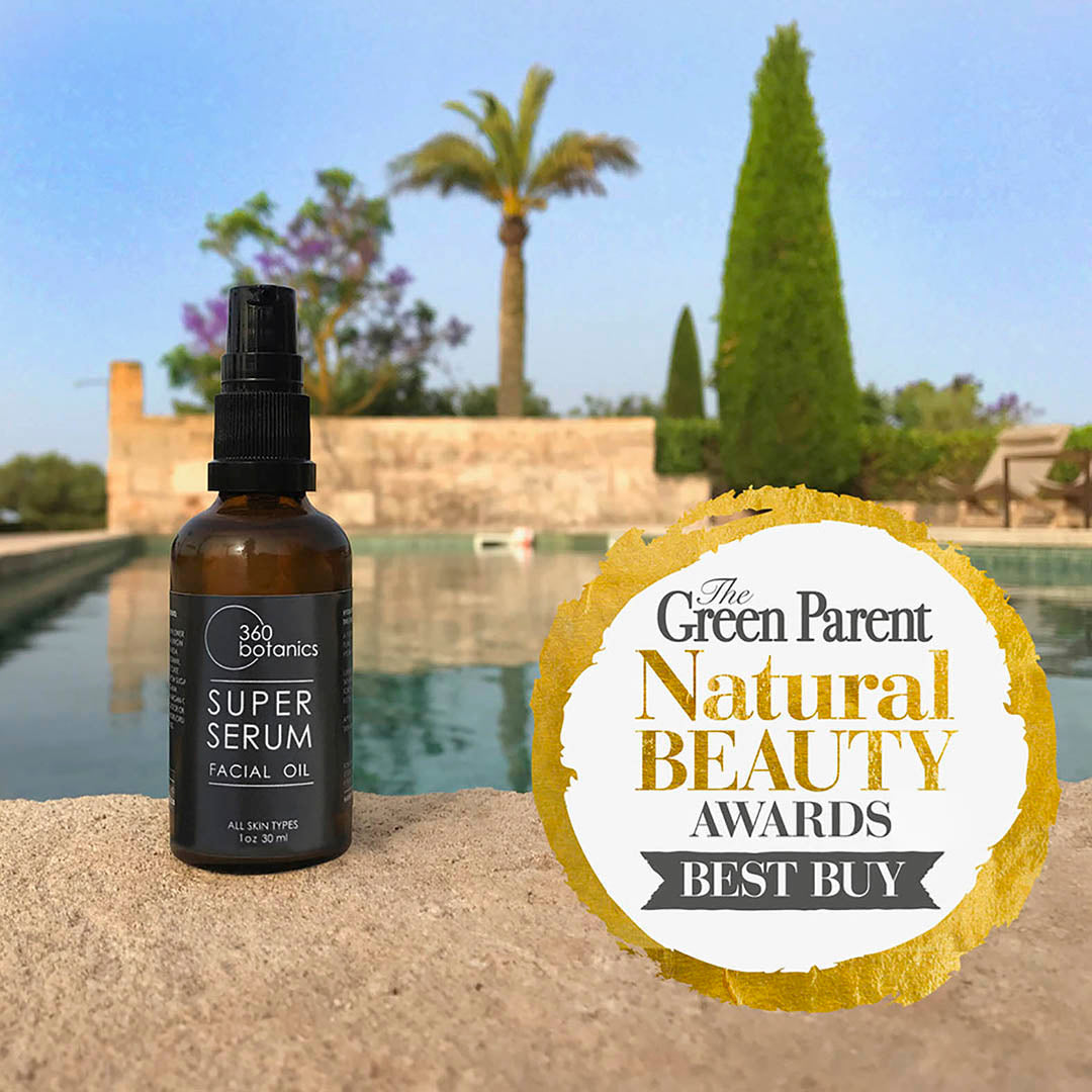 360 Botanics Super Serum Facial Oil bottle displayed outdoors against a picturesque Mediterranean backdrop, highlighting its award-winning status for natural beauty and skincare.