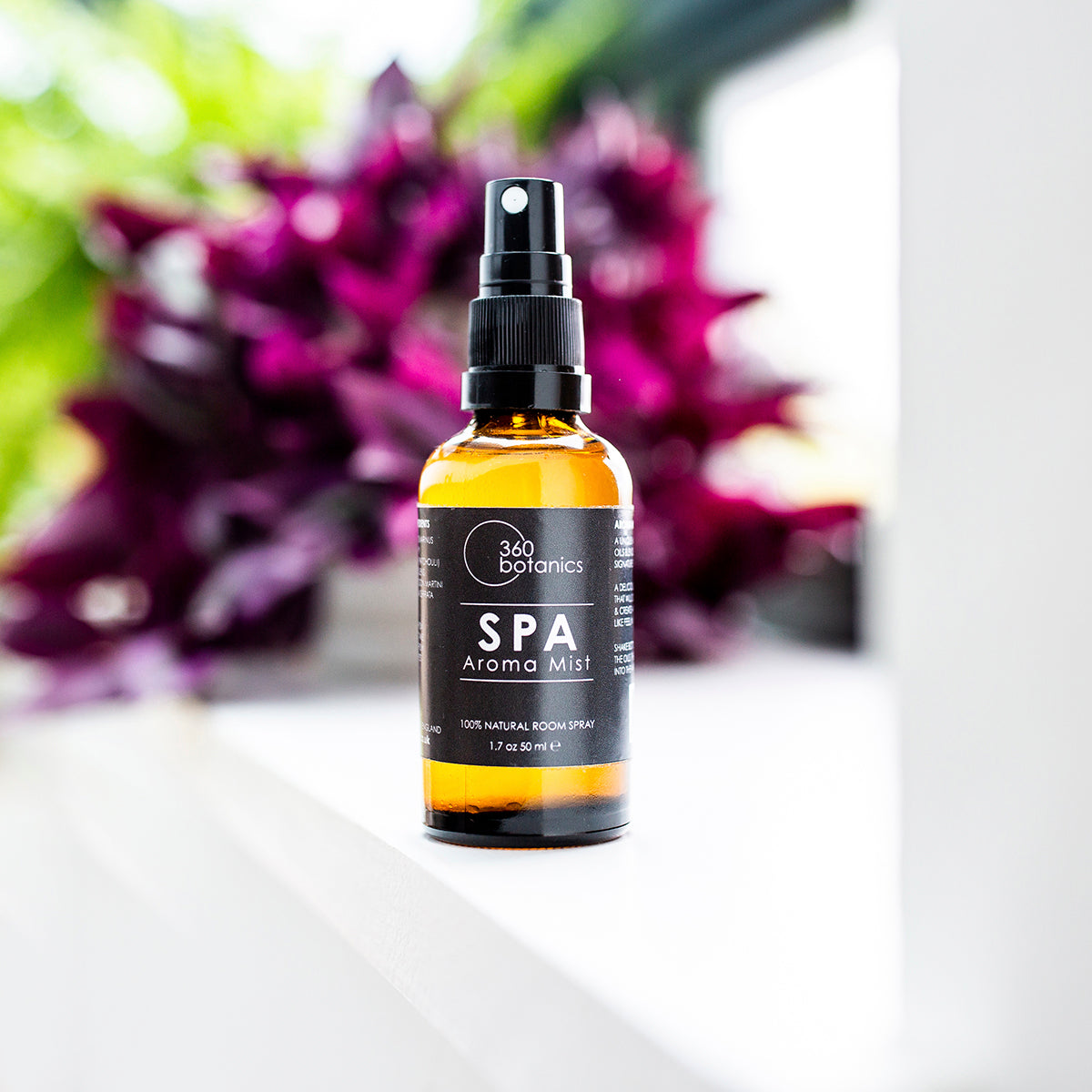 SPA aroma mist amber bottle on window sill, purple flower in background