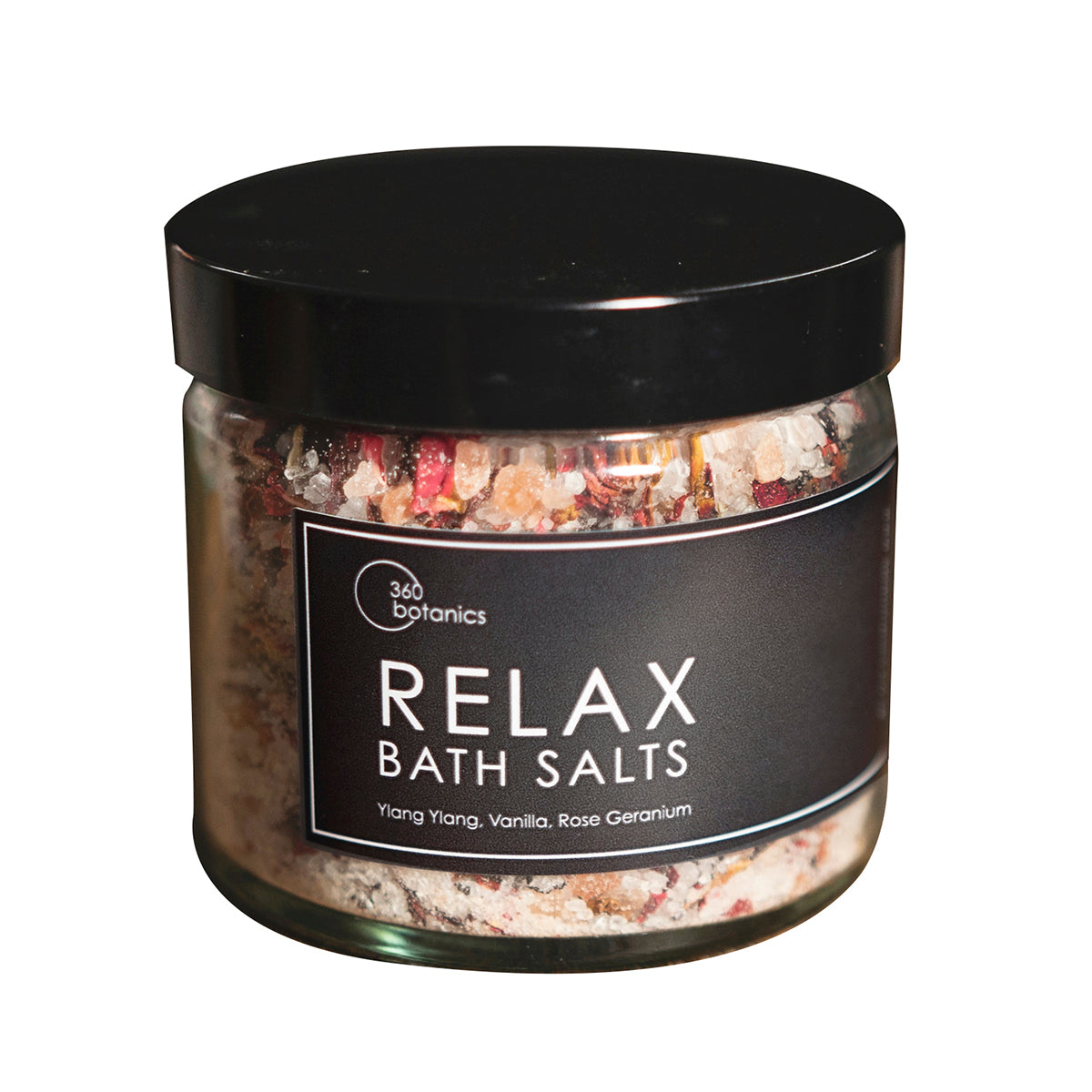 A transparent jar with a black lid labeled "RELAX Bath Salts" from 360 Botanics, filled with a mix of coarse bath salts and botanical pieces. The label also lists Ylang Ylang, Vanilla, and Rose Geranium as the scents, set against a white backdrop for clarity.