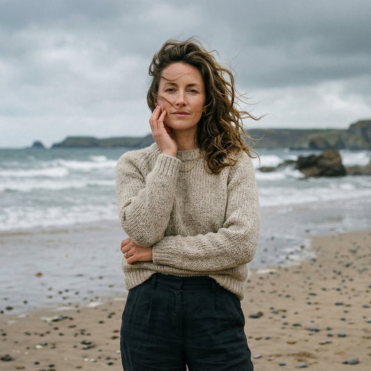 Woman on a windy English beach touching her face, illustrating the effects of salt water and sea air on skin.