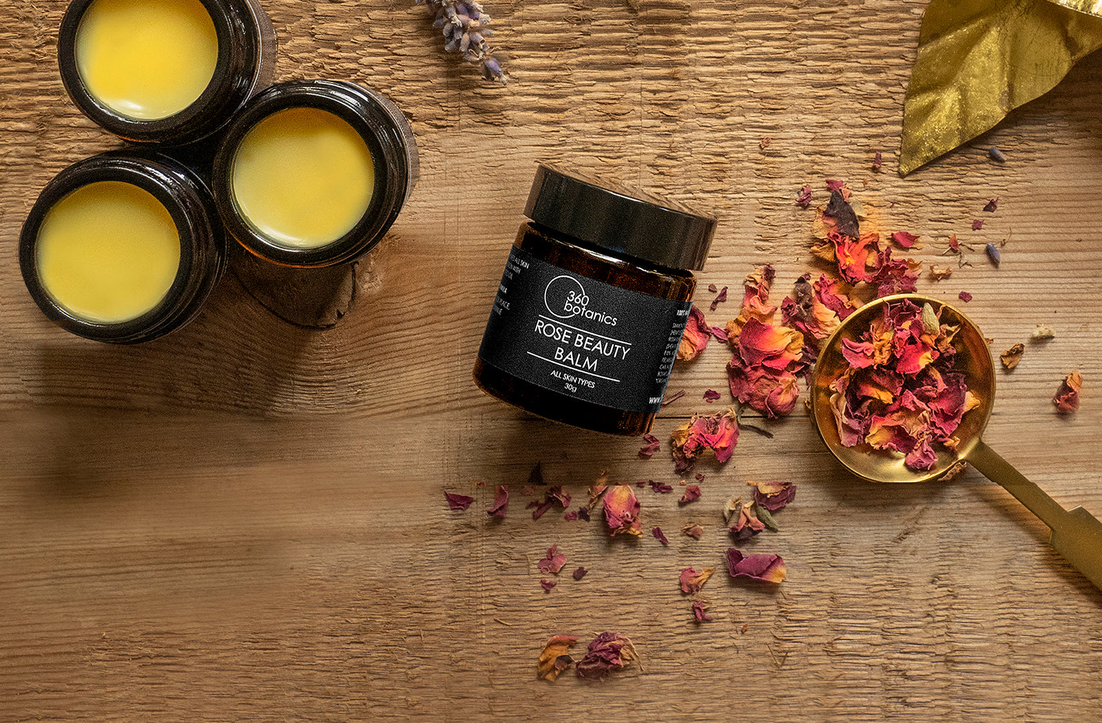 360 Botanics Rose Beauty Balm with dried rose petals on a wooden surface