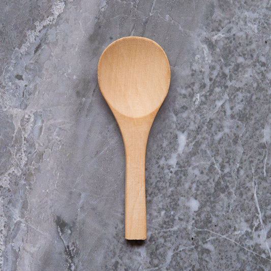A wooden spoon resting on a marble surface with natural grey veining,