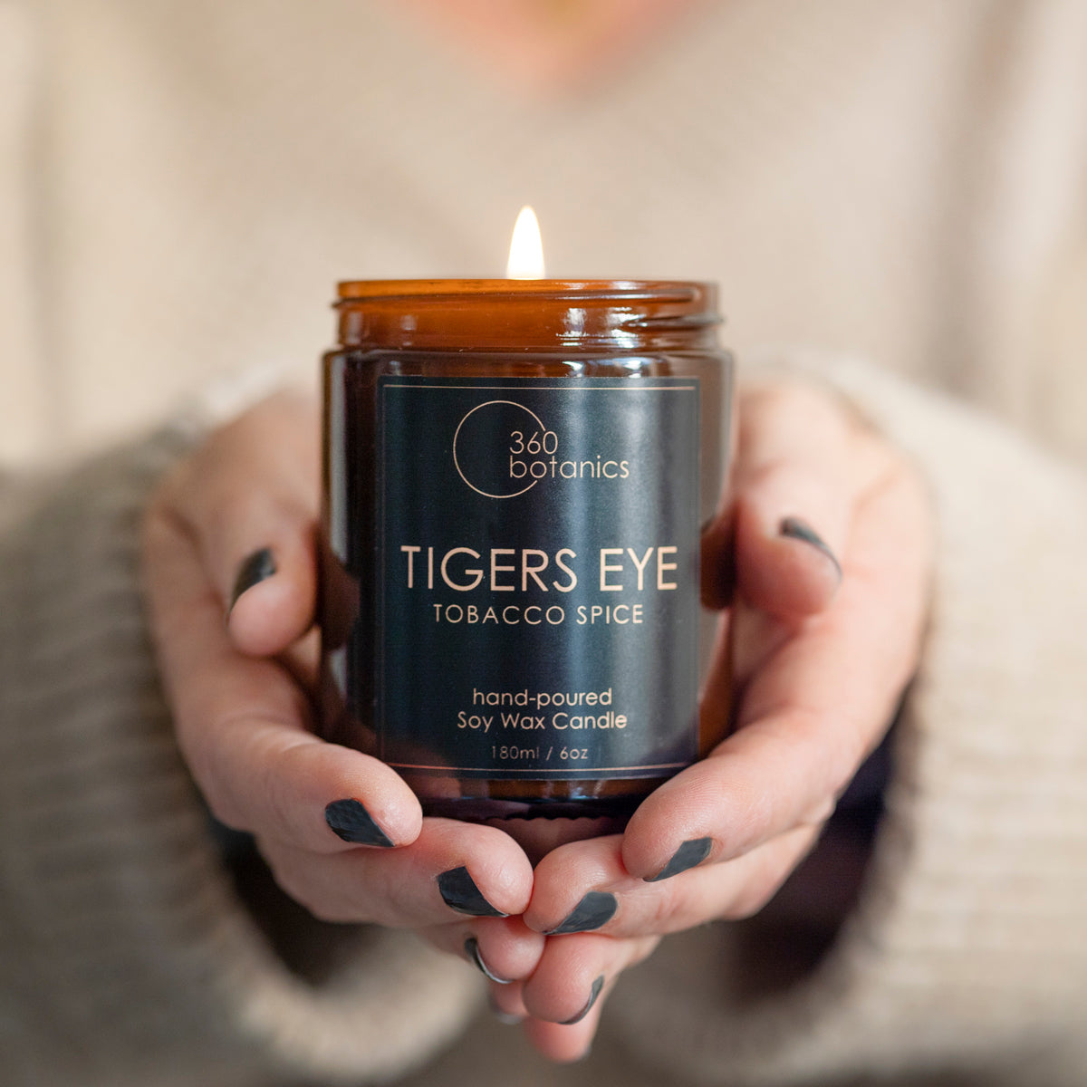 Tigers-eye candle in amber jar held between hands