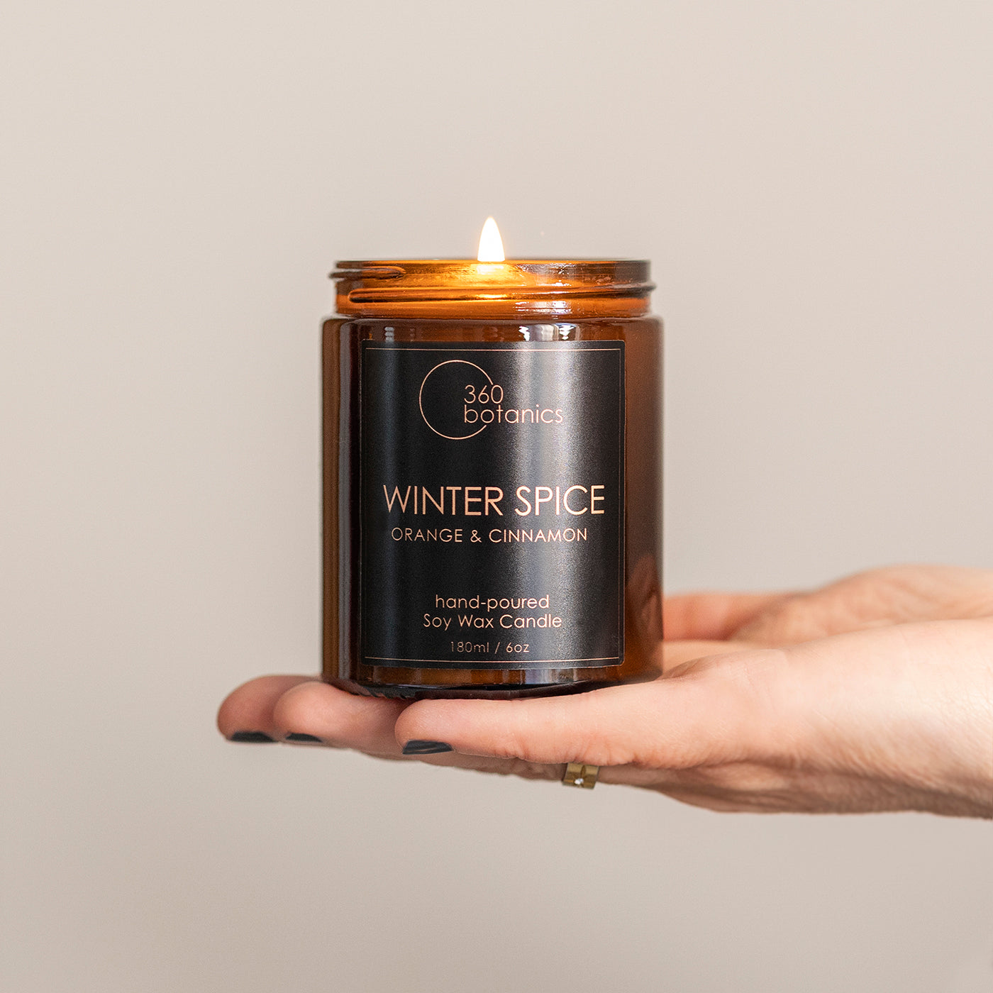 winter spice candle dark label on amber jar, held on hand white background