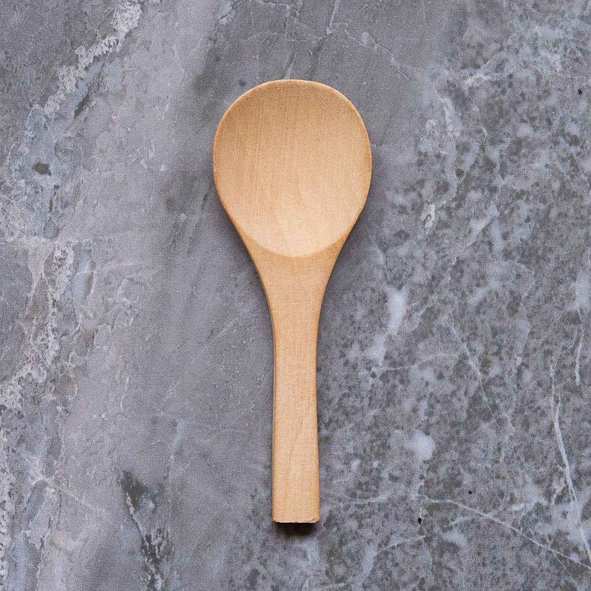 wooden body scrub spoon on grey marble surface