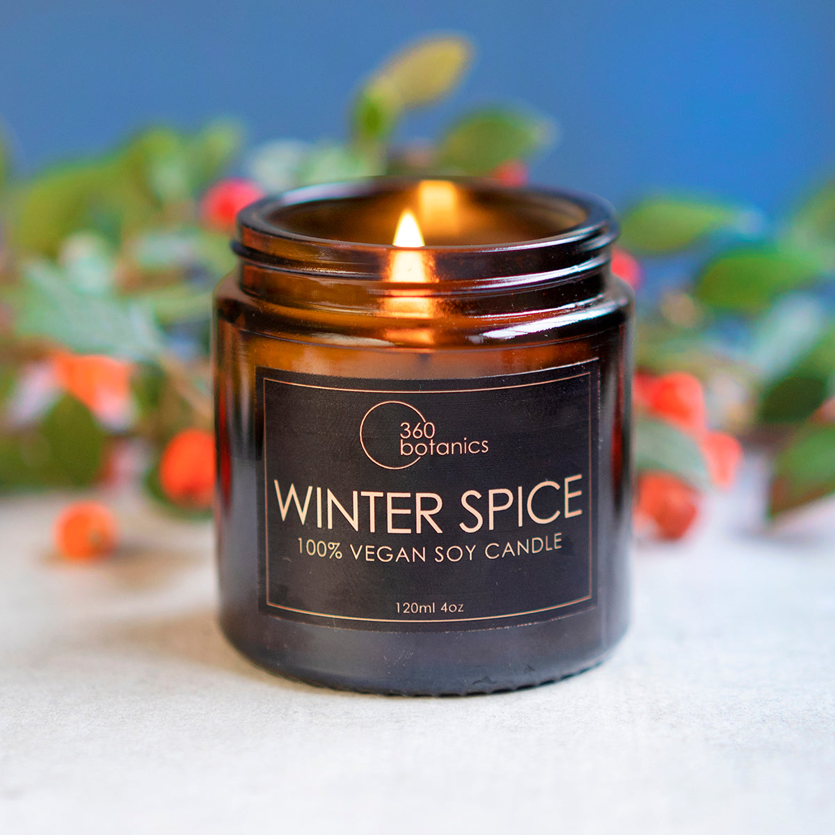 winter spice candle lit in Christmas environment with holly and berries